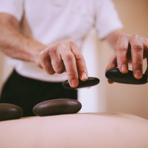 Practitioner's hands placing hot stones on a patient's back
