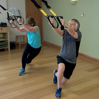 An older male and female taking part in a TRX class