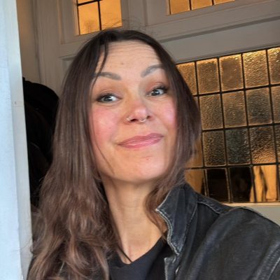 Anna-Ravenscroft-Ward-yoga-Exmouth.jpg Anna is smiling cheekily, her long brown hair loose around her face and neck. She is wearing two nose rings, and a black denim jacket.